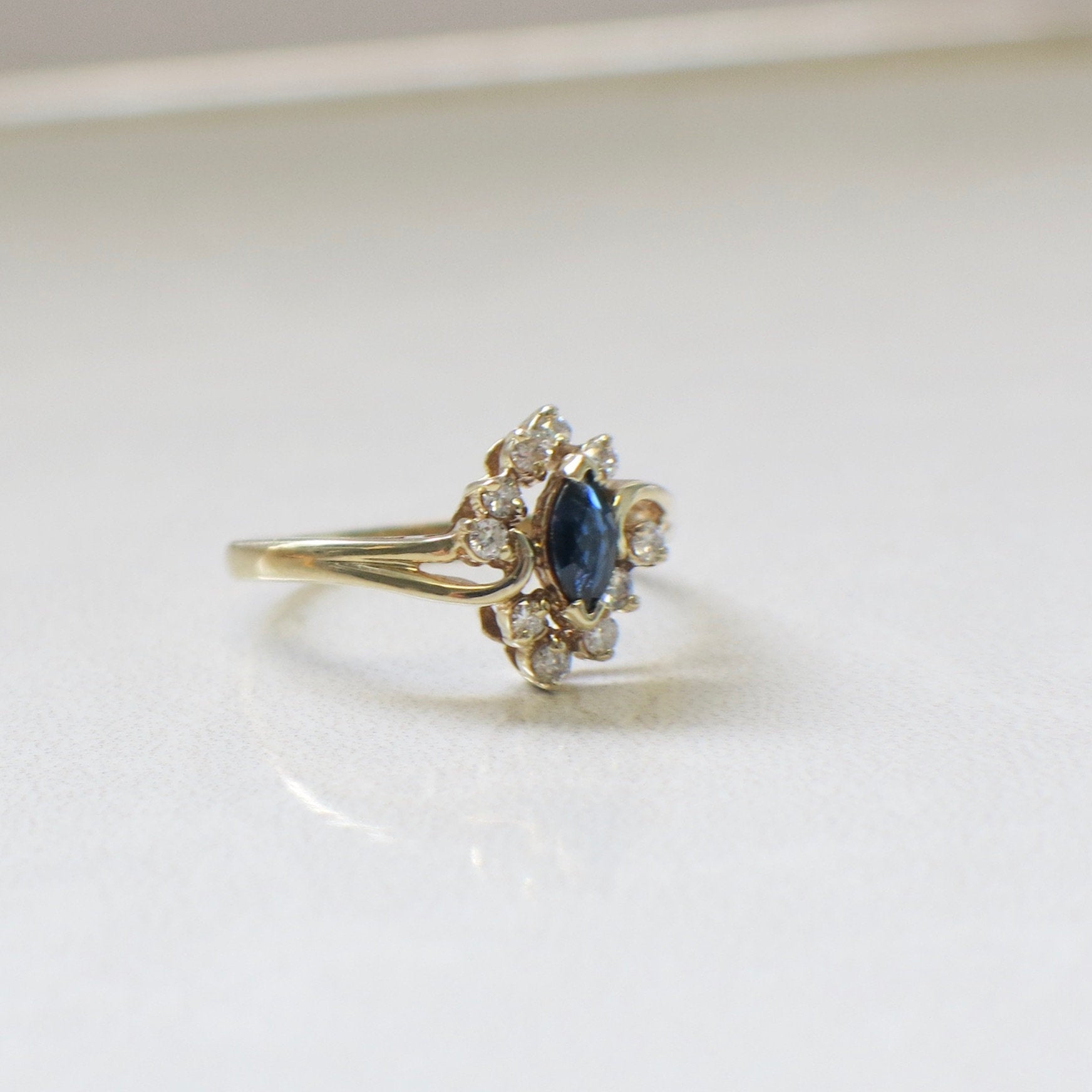 14K yellow gold marquise sapphire and diamond halo ring with vintage floral style, showcasing intricate design and sparkling gemstones.