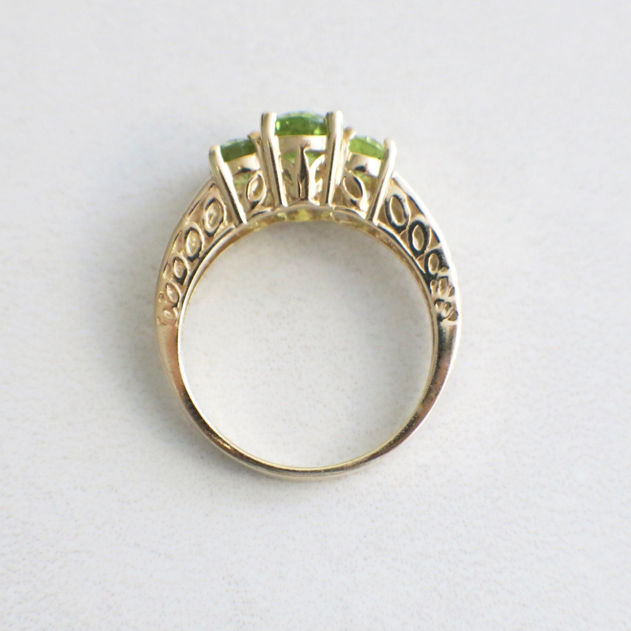 14K yellow gold peridot three-stone ring with oval-cut August birthstone, size 7, featuring elegant gemstone settings.