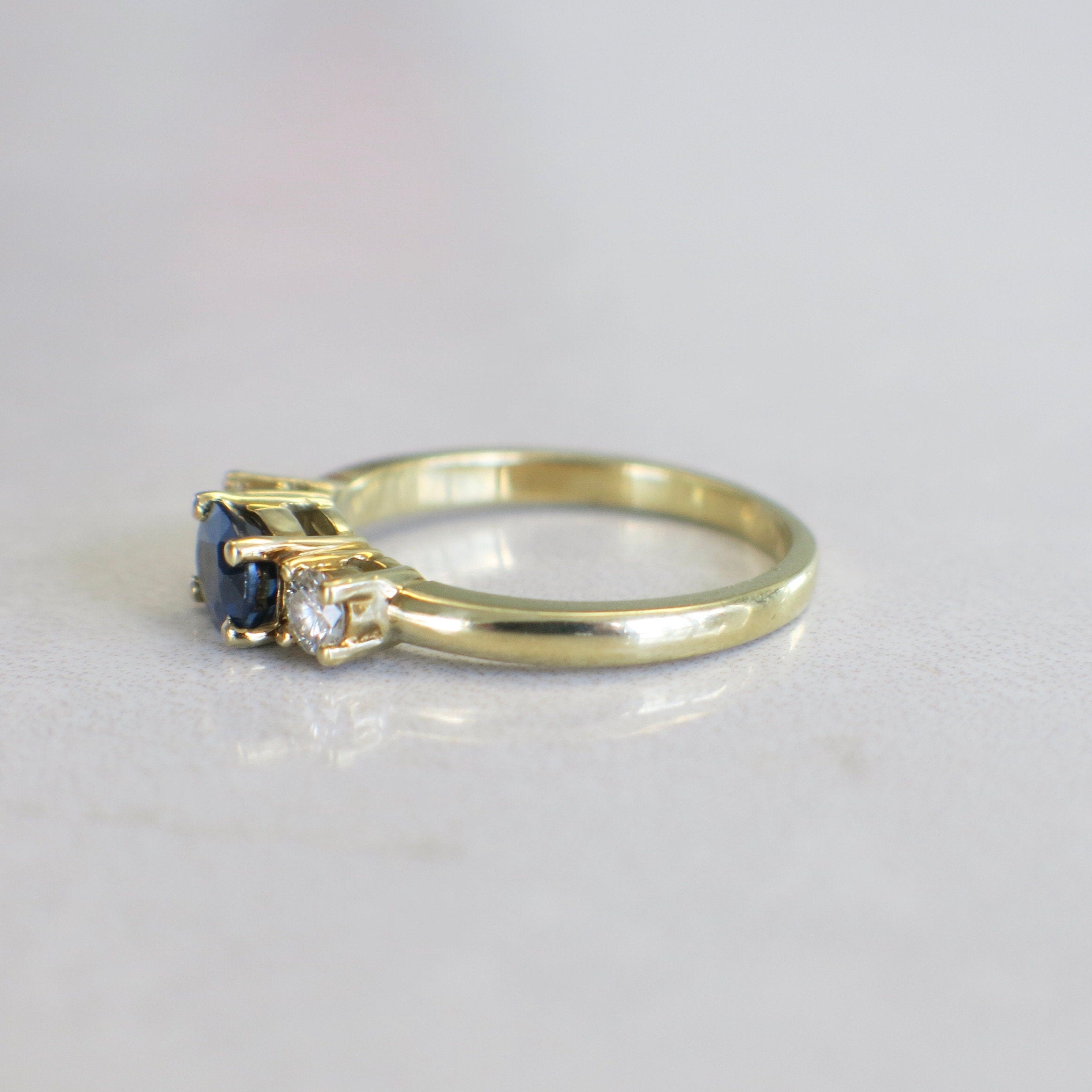 18K yellow gold sapphire and diamond three-stone ring featuring east-west sapphires and sparkling diamonds.