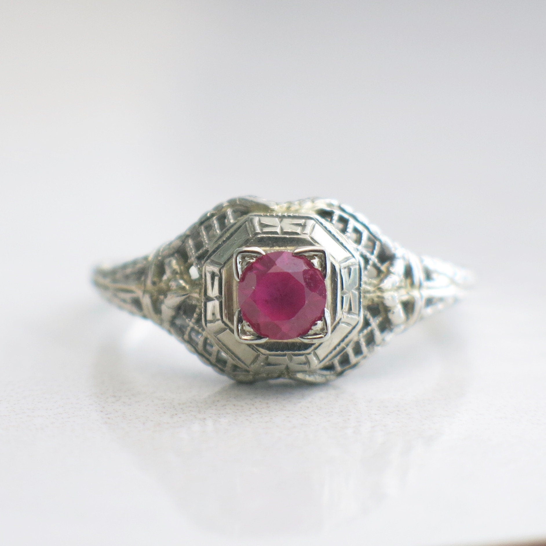 Art Deco filigree ring with pink sapphire set in 18K white gold, size 7.75, featuring intricate metalwork and vintage design.
