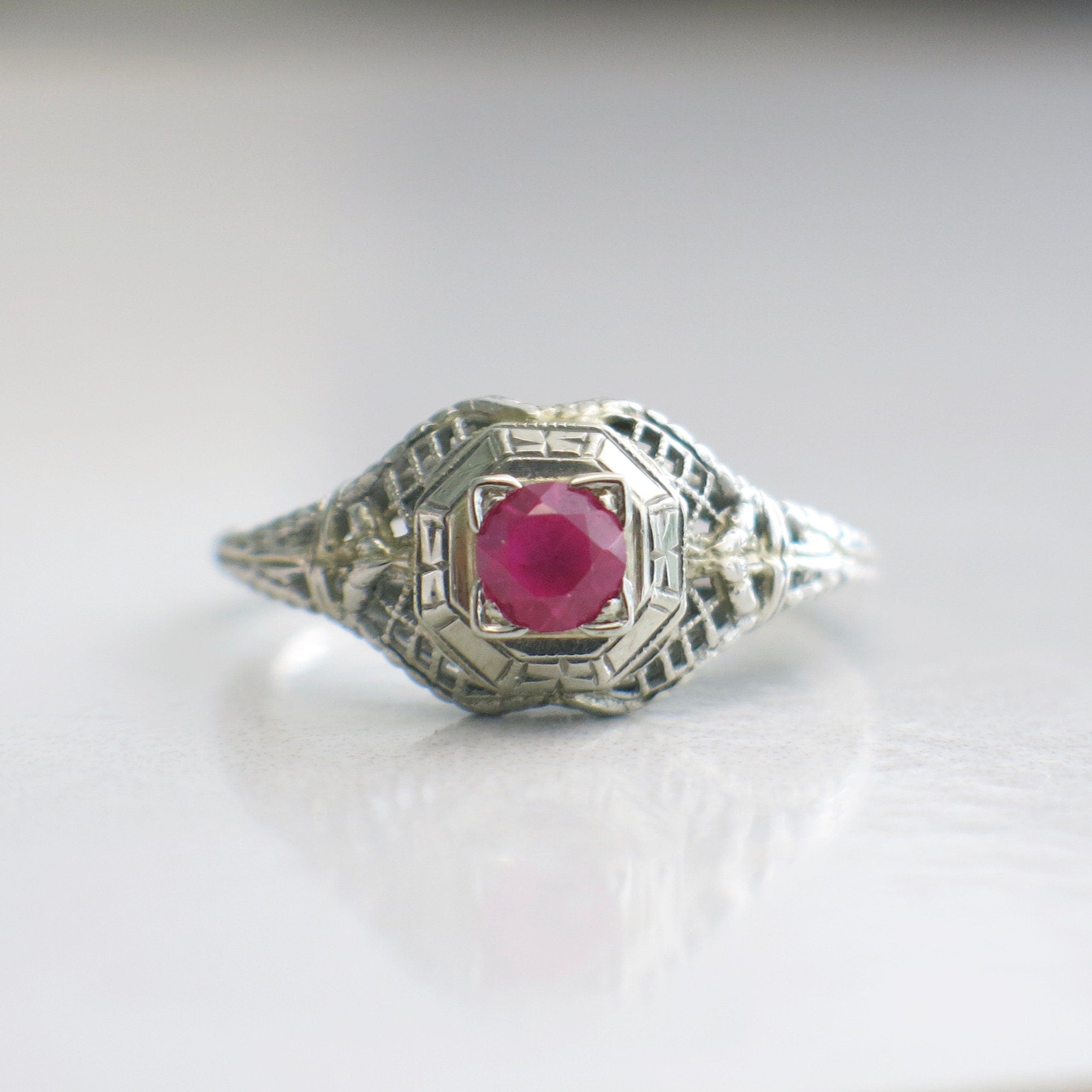 Art Deco filigree ring with pink sapphire in 18K white gold, size 7.75, featuring intricate metalwork and gemstone accents.