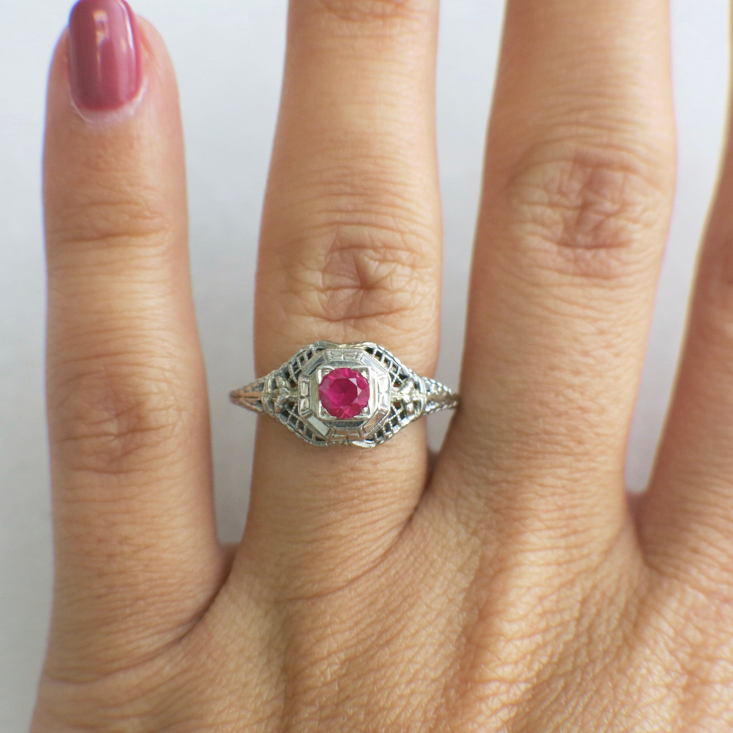 Art Deco filigree ring in 18K white gold with pink sapphire, size 7.75, showcasing intricate metalwork and gemstone detailing.