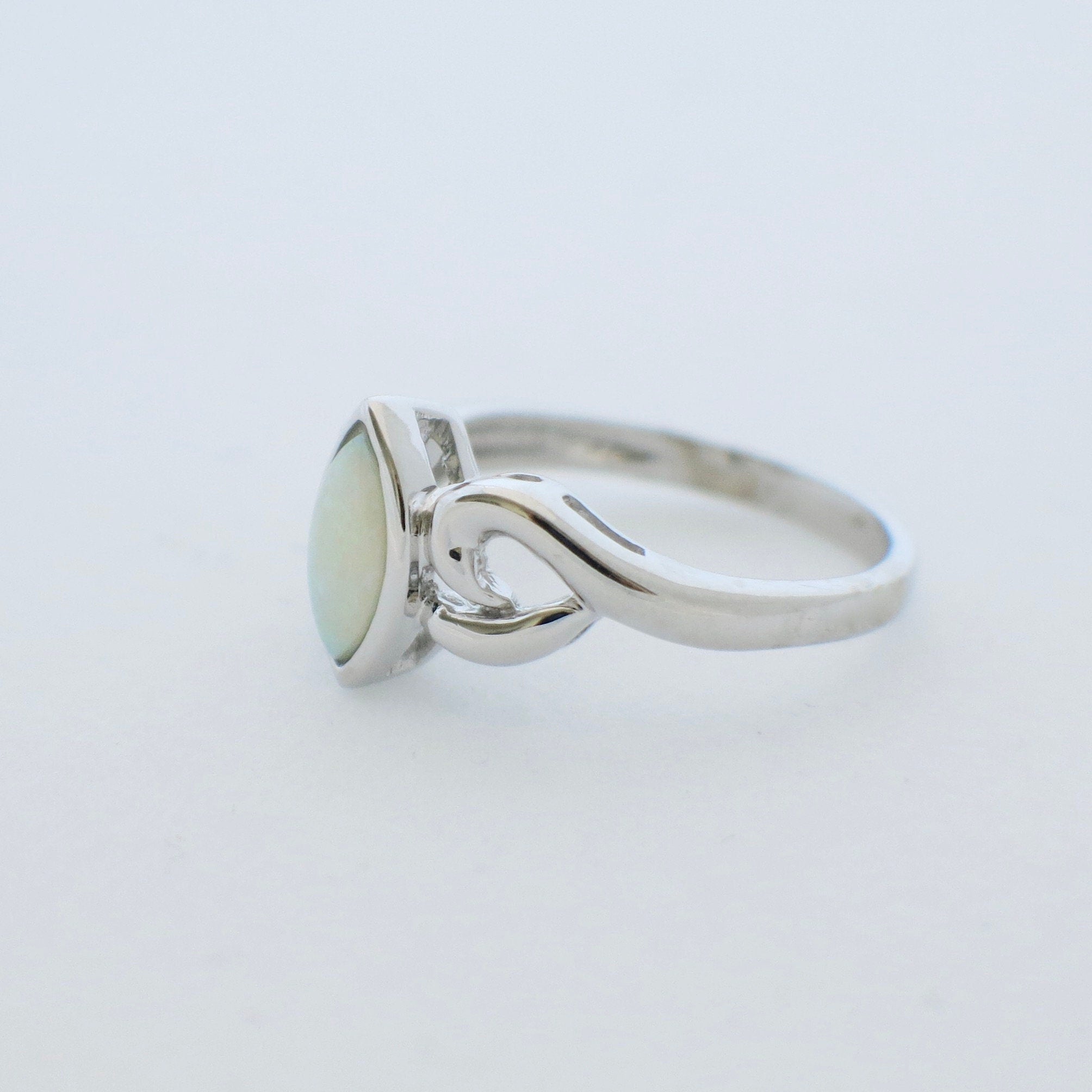 Marquise opal ring in 14K white gold with bezel setting, size 5.5, featuring a vibrant cabochon gemstone.