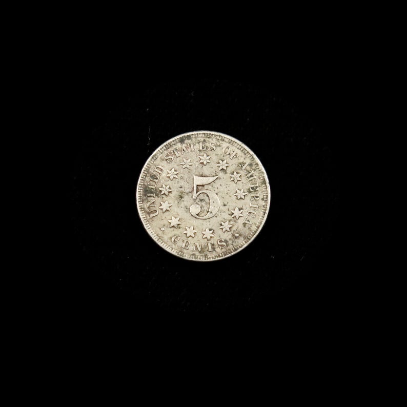 1867 Shield Nickel U.S. five-cent coin with no rays, good condition, raw, featuring classic shield design, from Black Market LLC.