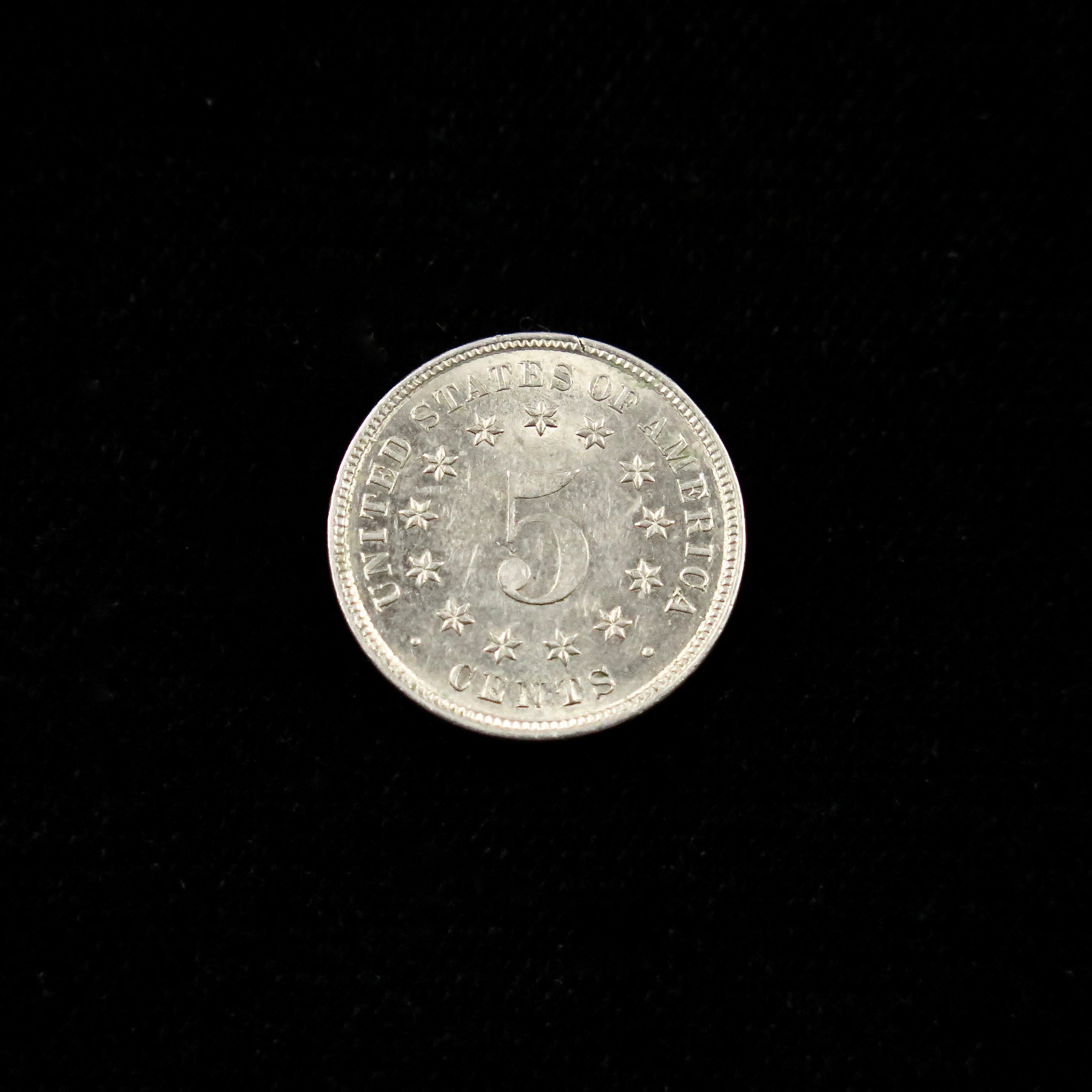 1883 Shield Nickel in Mint State, final year U.S. five-cent coin, raw condition, displayed with detailed view of the nickel's design.